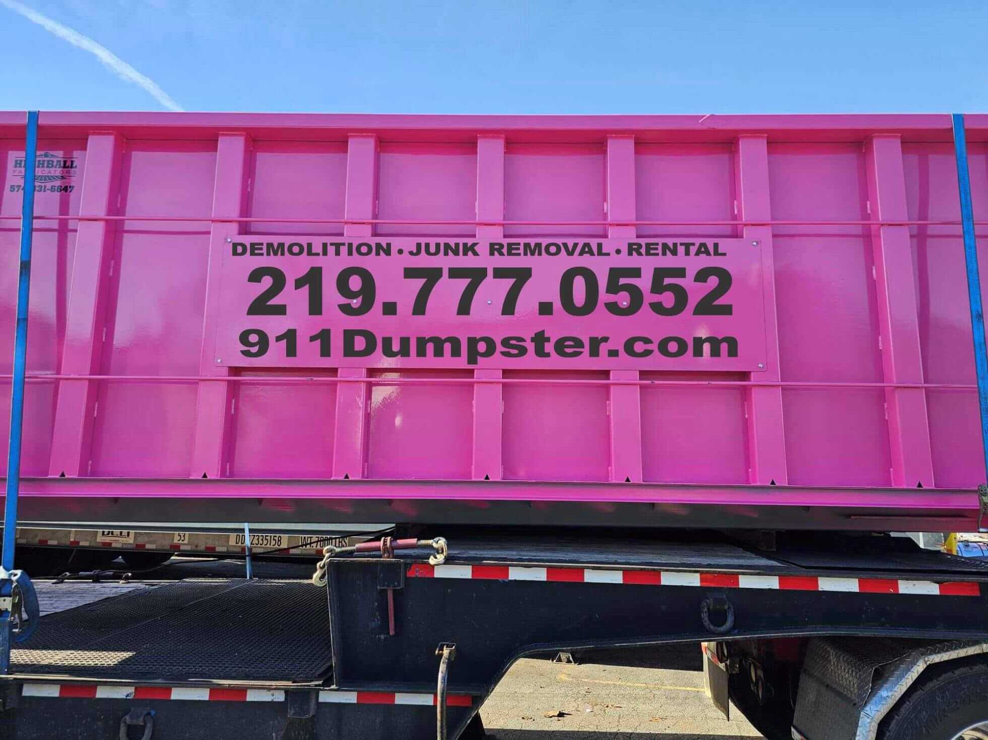 Vivid pink commercial dumpster with demolition, junk removal, and rental services listed, contact number 219.777.0552 and website 911Dumpster.com prominently displayed, available in Lake, Porter, and LaPorte County, Indiana